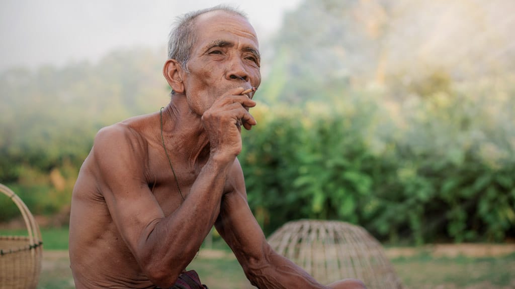 Wir werden sehen Alter Mann sitzt und raucht eine Zigarette