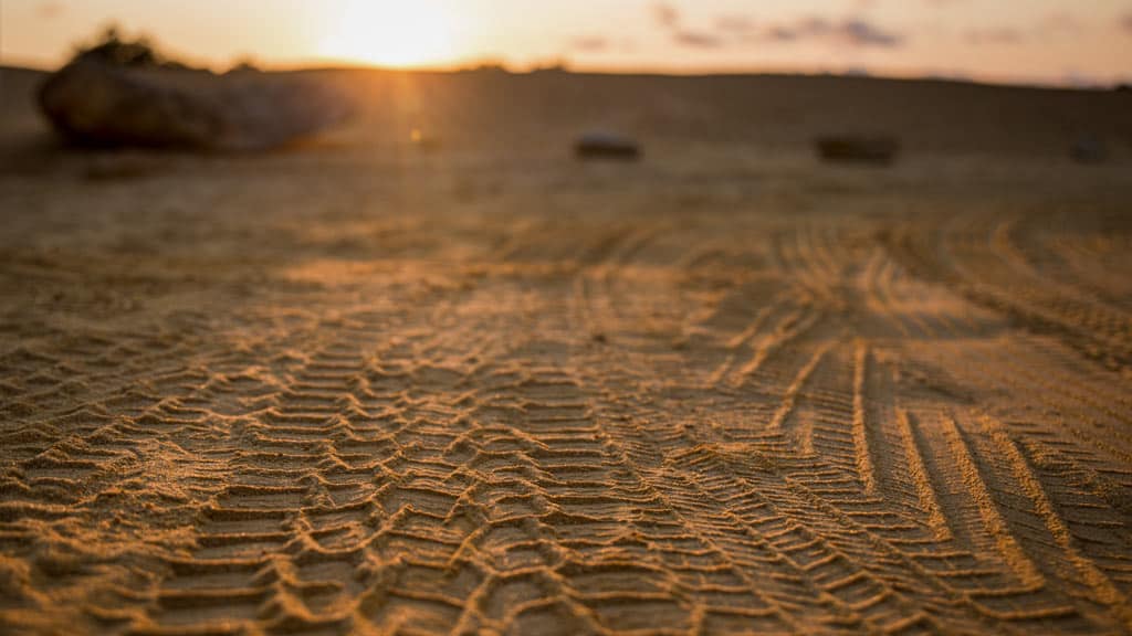 Im Sand hinterlassene Reifenspuren im Gegenlicht